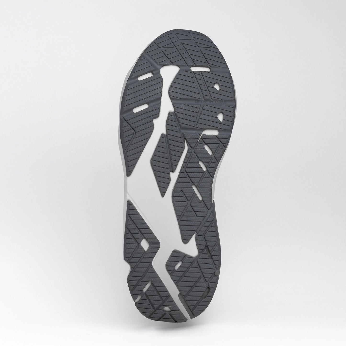 Close-up view of the grey and white rubber outsole of a running shoe, showing its textured tread pattern for grip and flexibility.