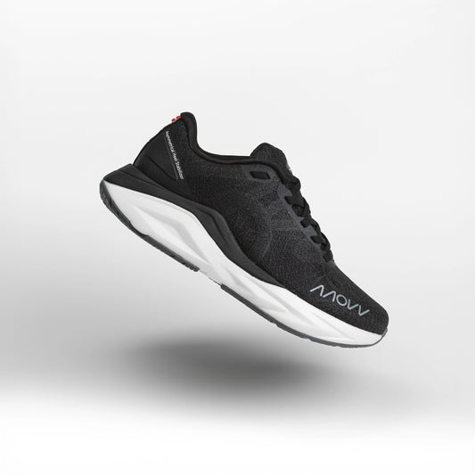 A black athletic running shoe with white midsole photographed against a light gray background. The shoe features a dark mesh upper material, black laces, and MOVV branding visible on the side.