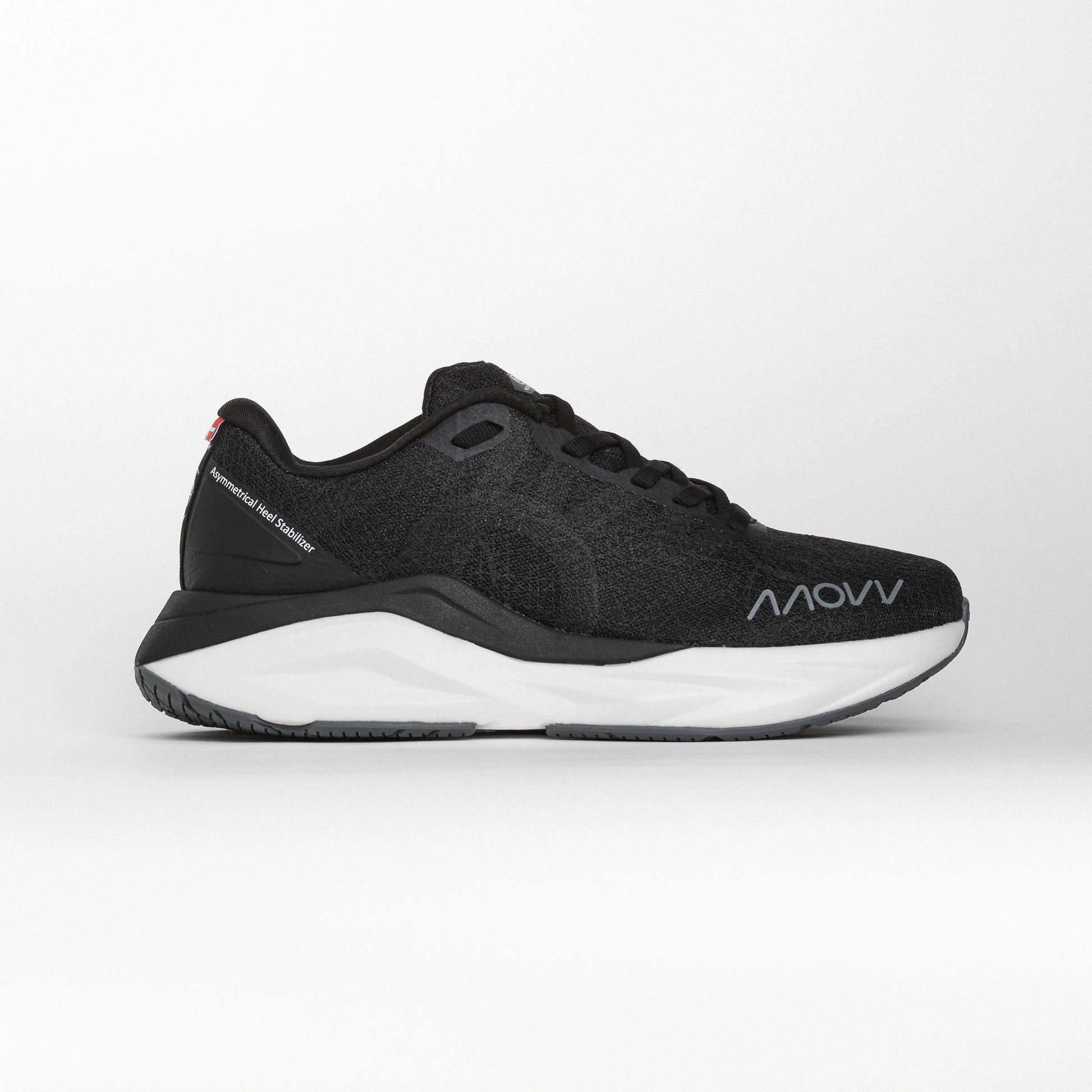 Side profile of a black MOVV running shoe with a white midsole and grey outsole, featuring the brand logo near the toe and an asymmetric heel stabilizer for support.