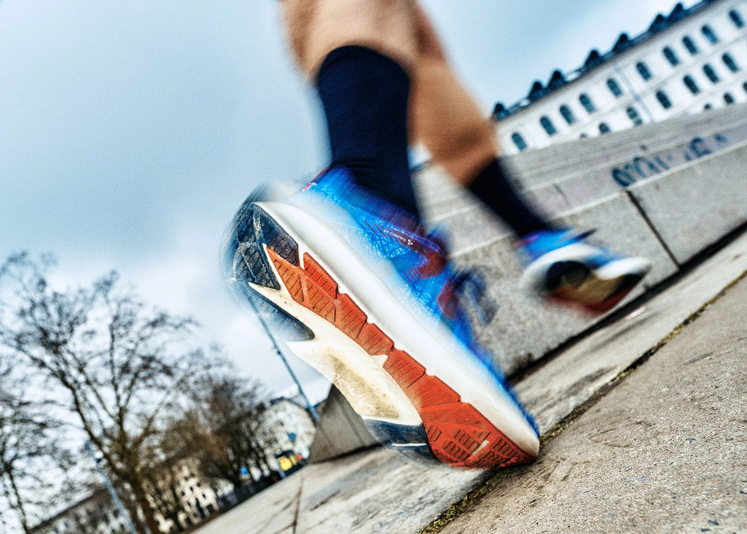 Close-up of a person wearing colorful MOVV running shoes on a city street.